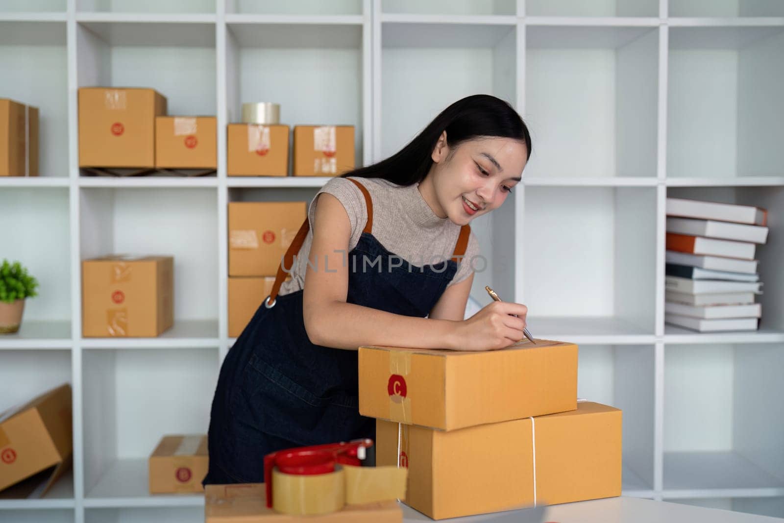 Woman asian in an online store check the customer address and package information on box. Online shopping concept.