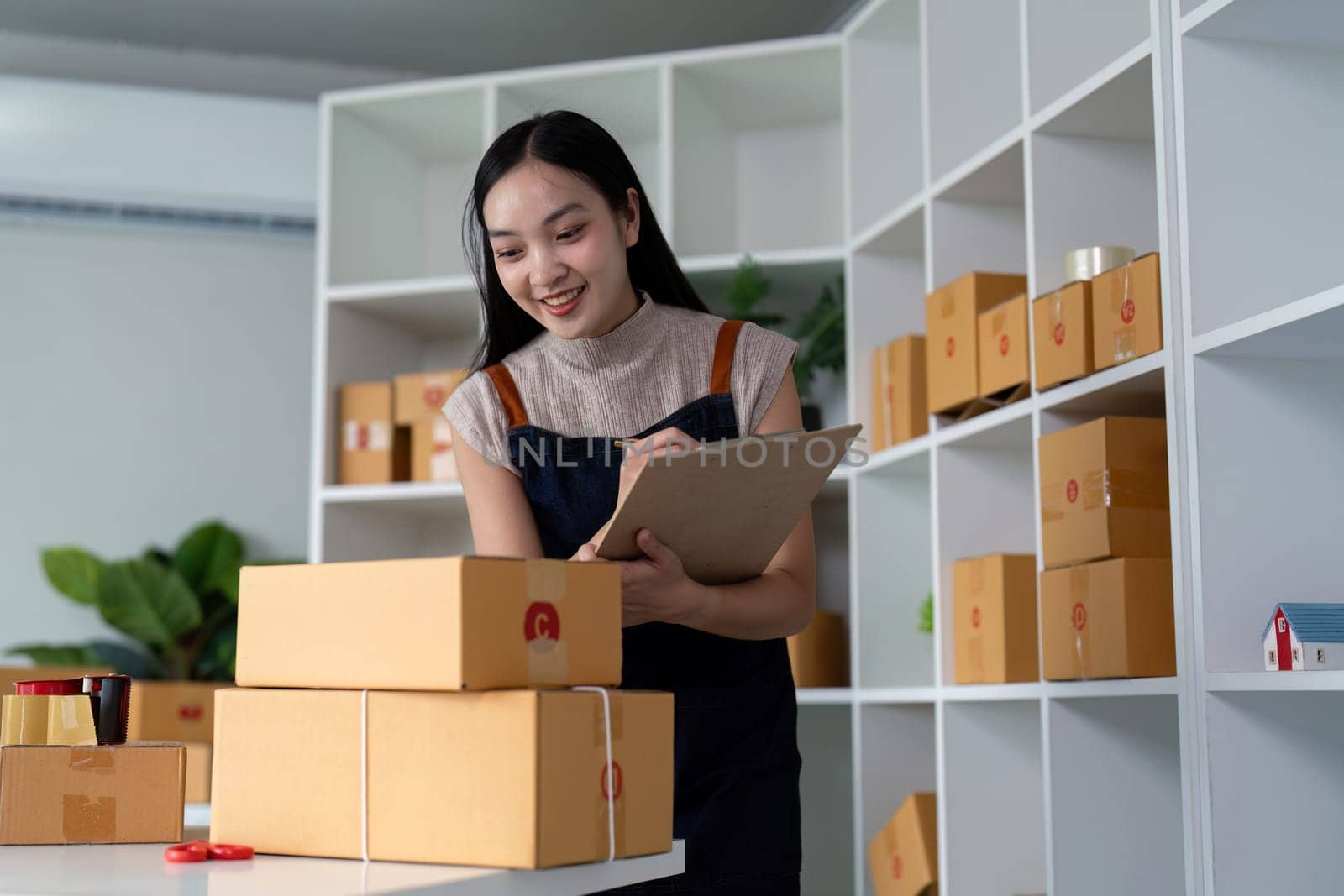Woman entrepreneur prepare parcel box and check online order on laptop computer for commercial checking delivery. online marketing, packing box, SME seller. startup business concept.