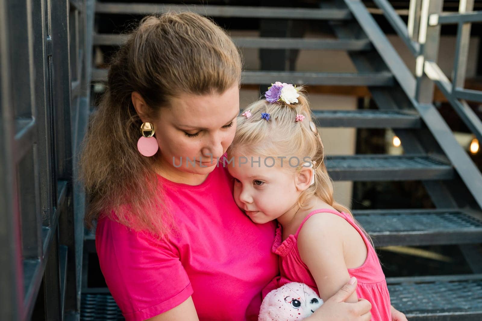 Child girl with cochlear implant with her mother spend time outdoor. Hear impairment and deaf community concept. Deaf and health concept. Disability and inclusion. Copy space by Satura86