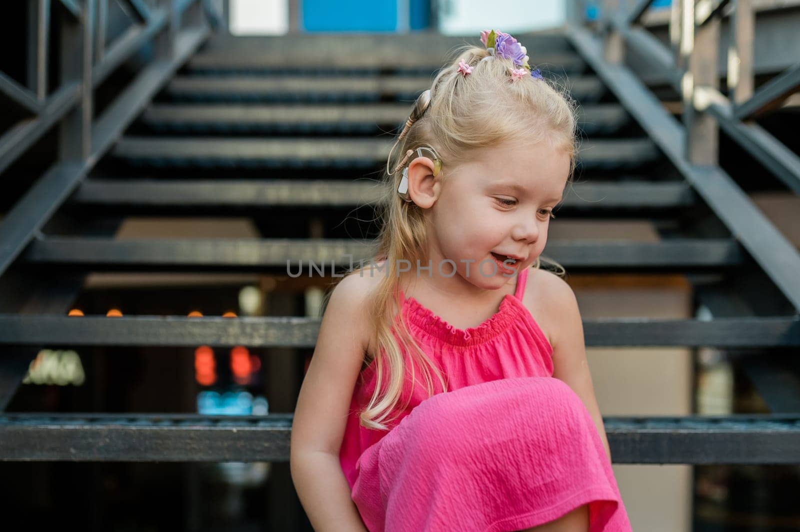 Child girl with hearing aids and cochlear implants having fun outdoor speak and playing. Copy space and empty place for advertising.