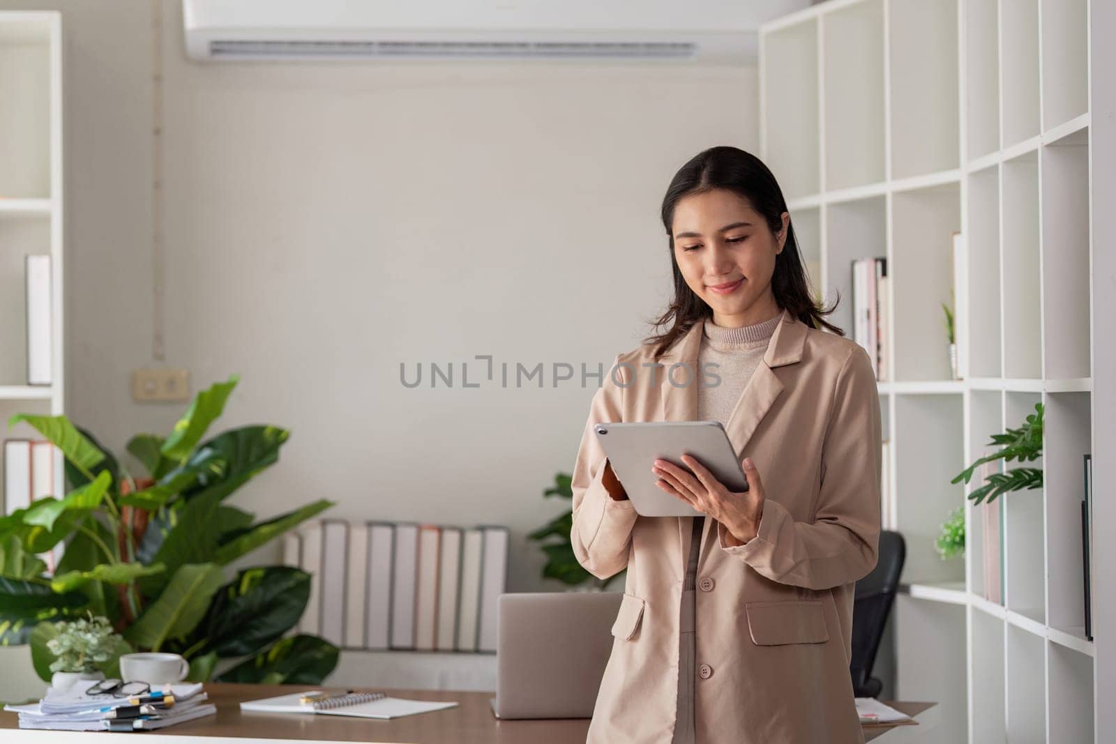 Smiling professional business woman entrepreneur holding digital tablet pad standing in office at work.