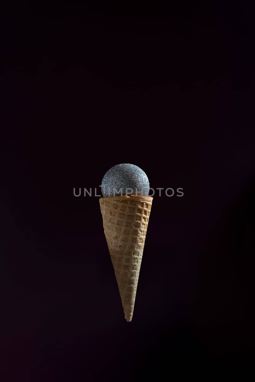 A microphone is placed inside of an ice cream cone. The cone is upside down and the microphone is suspended in the air. by Matiunina