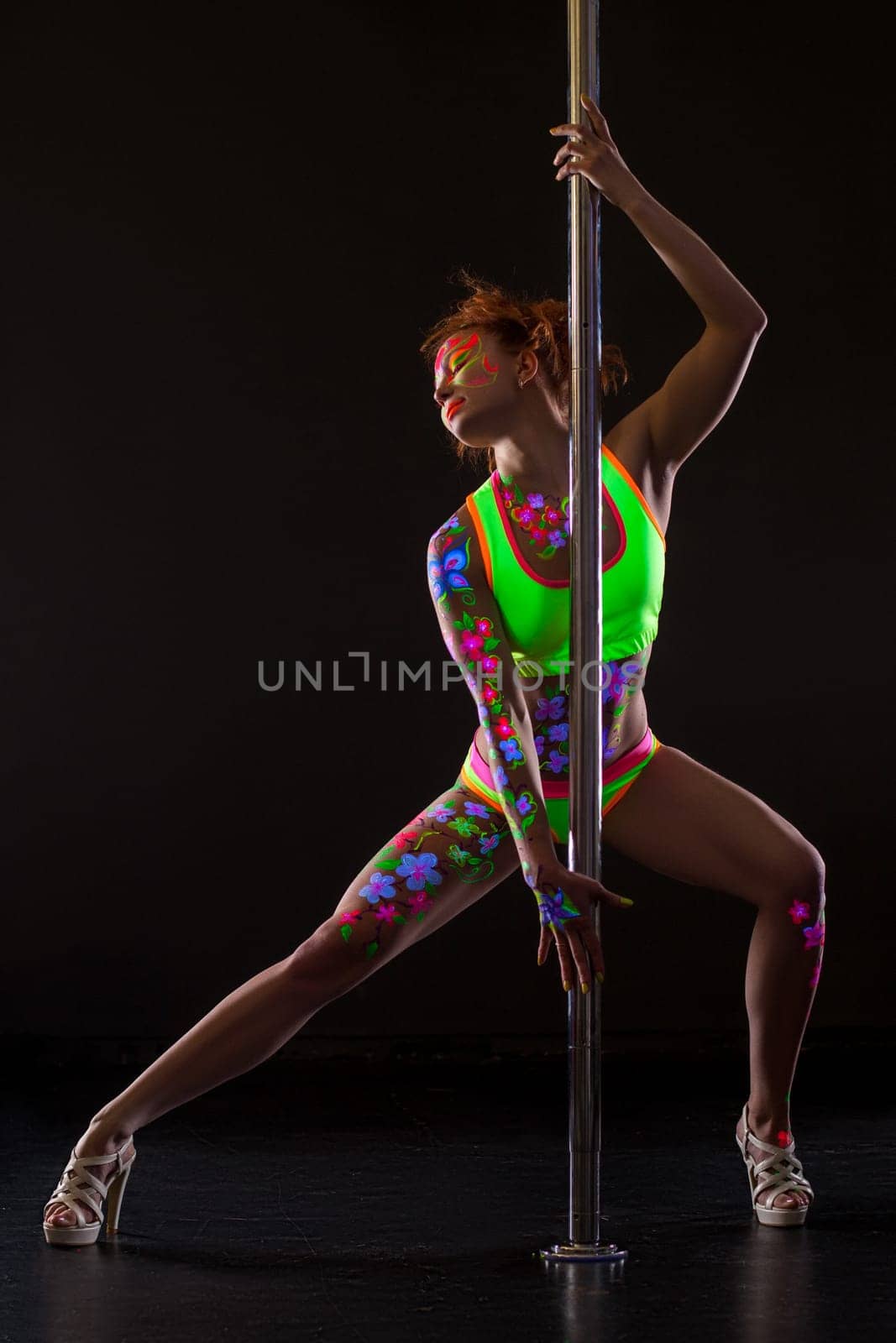 Beautiful pole dancer with glowing patterns on her body