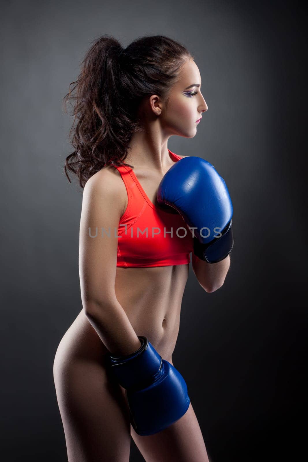 Nude. Beautiful young woman posing in boxing gloves