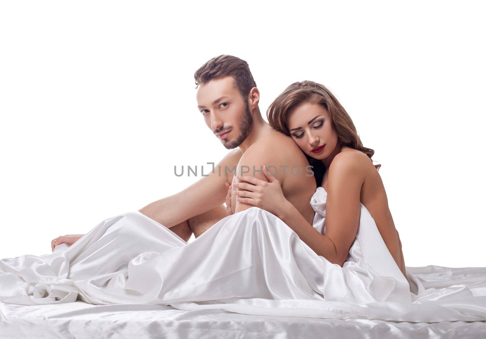 Erotica. Loving couple posing in bed, isolated on white