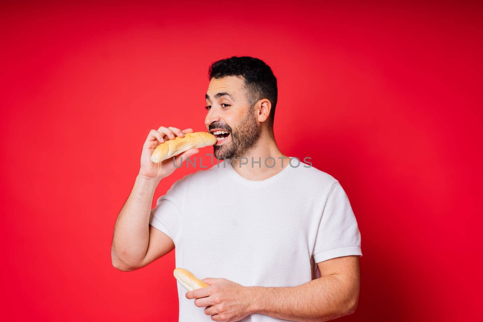 Man with freshly baked bread in hands isolated on red background studio