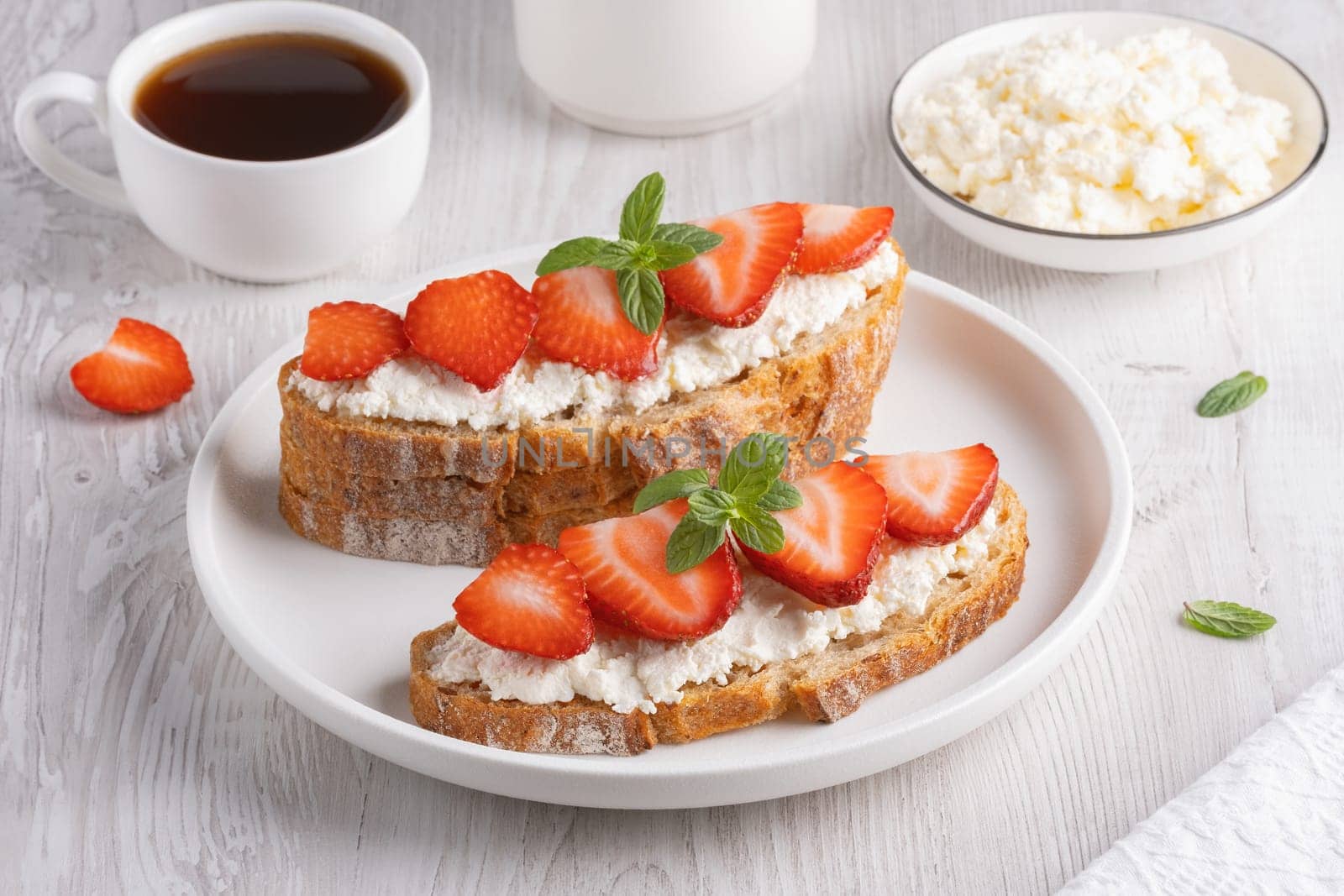 Homemade Crispbread toast with Cottage Cheese and Strawberry on white wooden board by NataliPopova