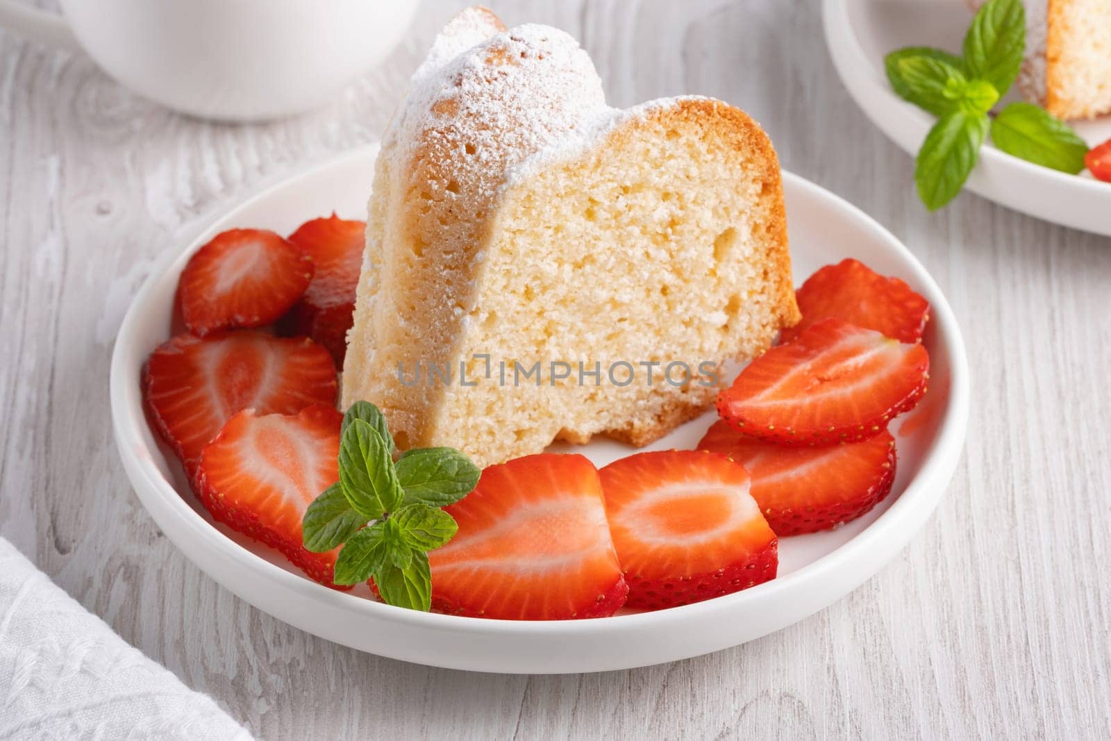 Piece of cupcake with strawberries on a plate.