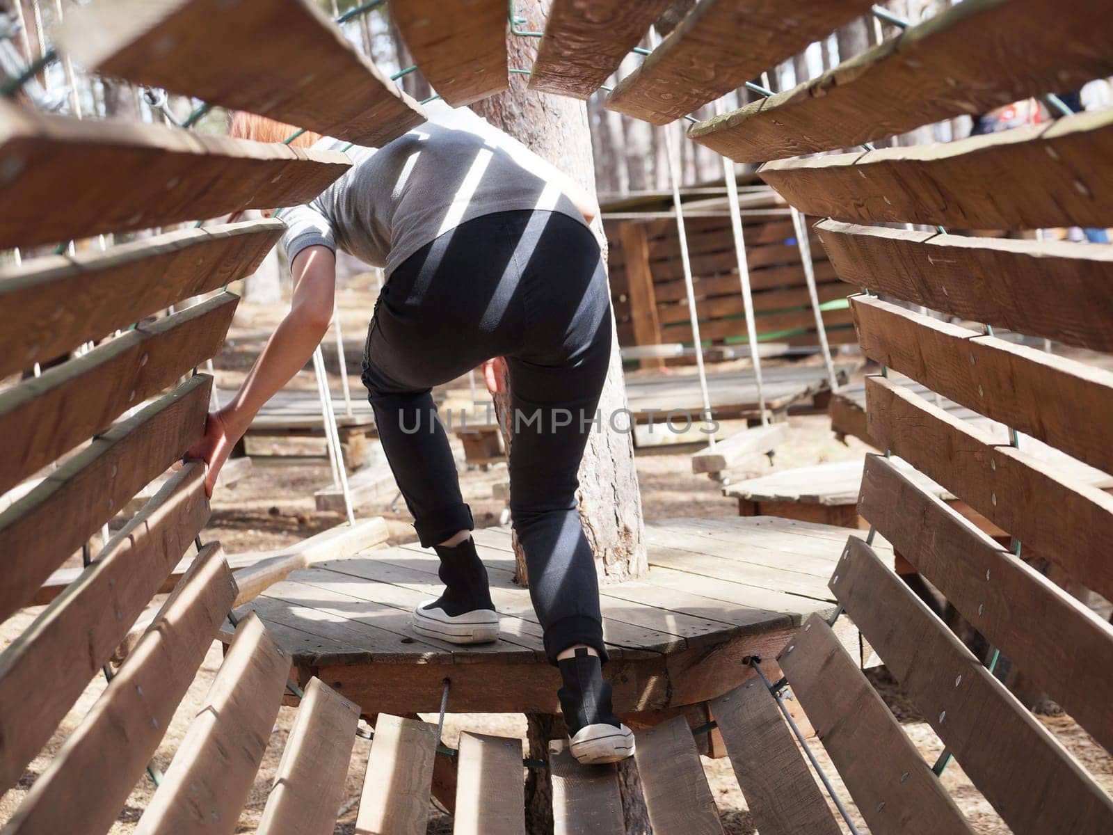 girl coming out of a wooden tunnel obstacle course outdoors.