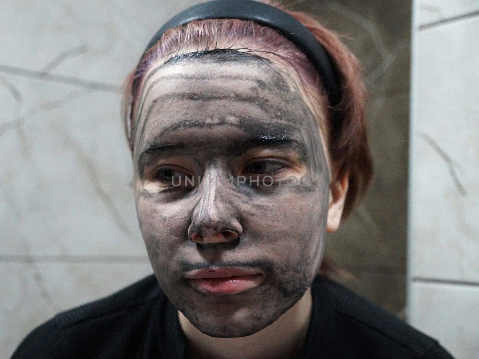 portrait of a girl with a charcoal face mask close-up.
