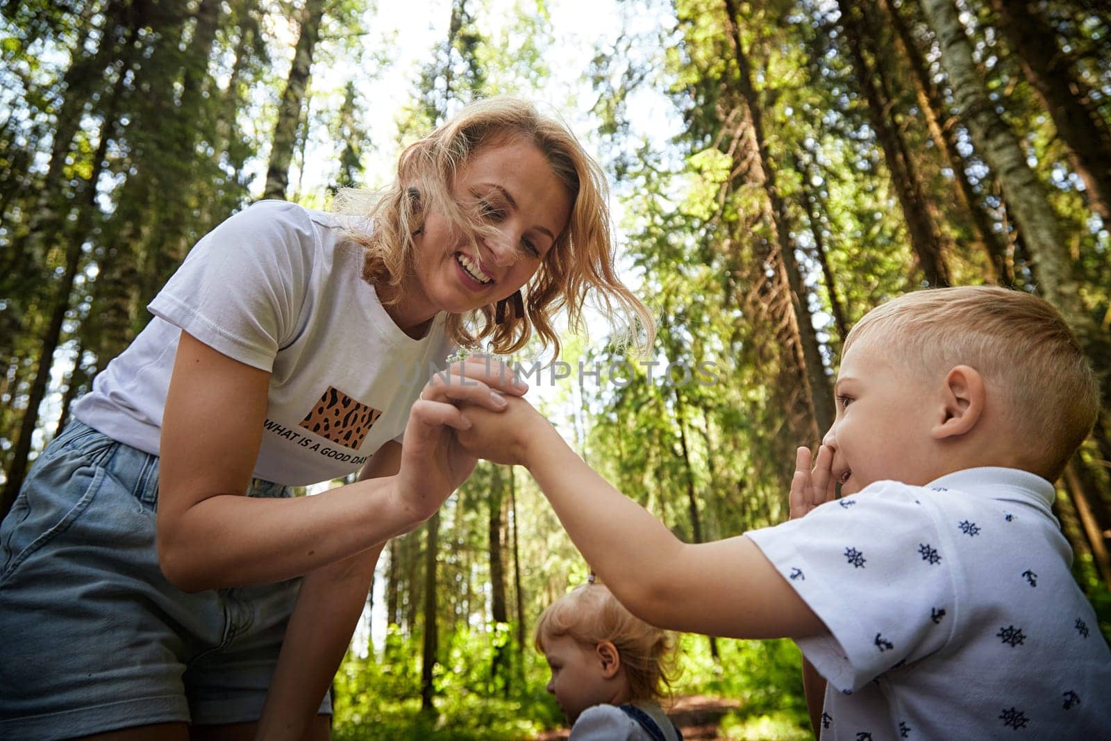 Mother and Son Enjoying a Sunny Day in the Forest and daughter on the background. Life style by keleny