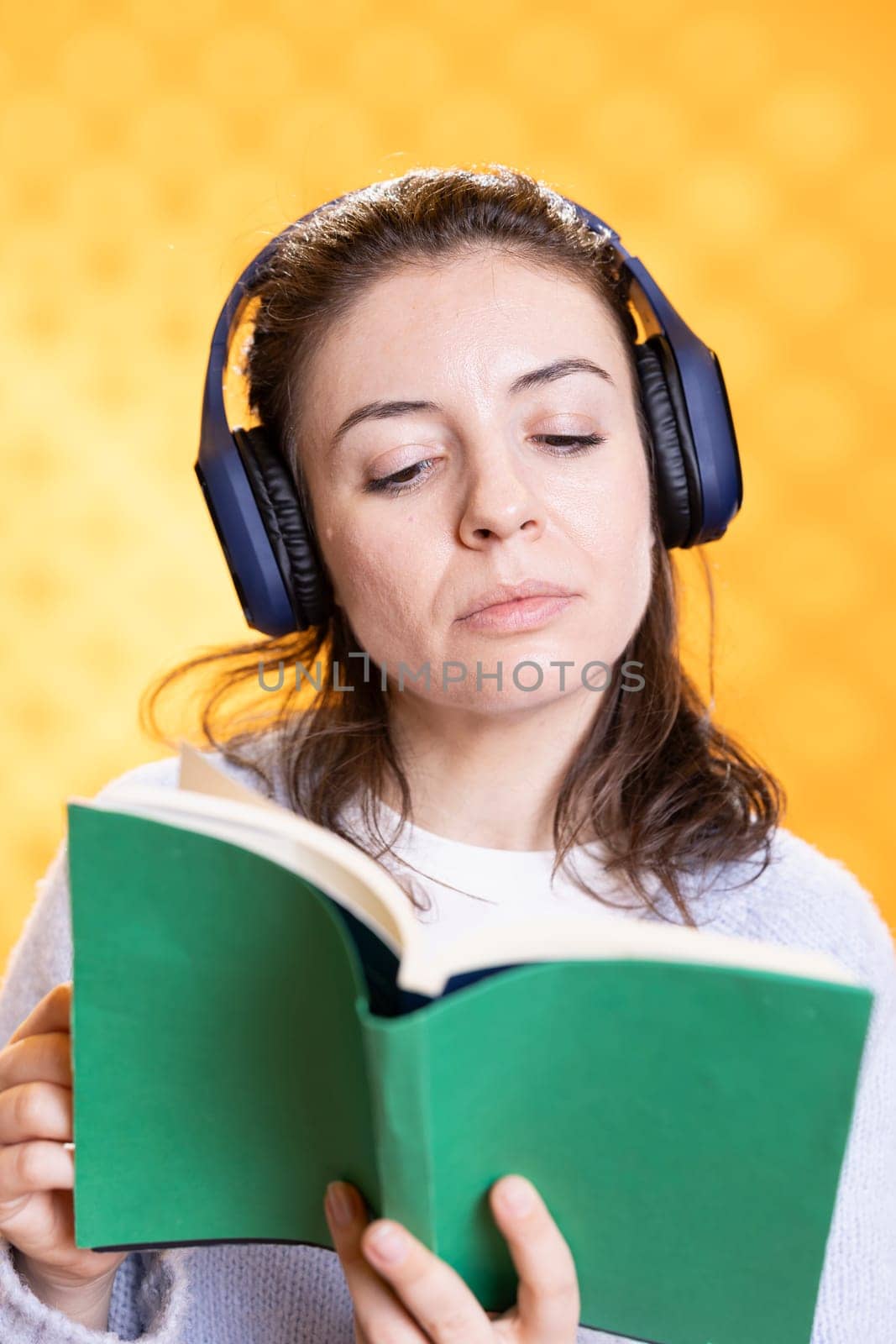 Geek with novel in hand hearing songs through headphones, entertainment concept by DCStudio