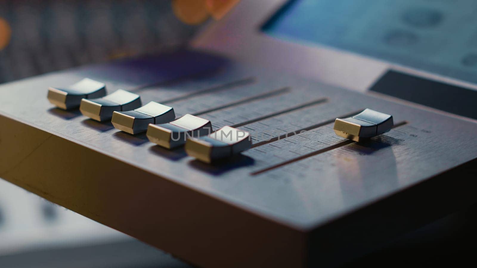 Sound engineer operating on motorized faders controller in professional studio, editing and mixing tracks to create a song. Audio technician works with sliders and soundboard panel. Camera A.