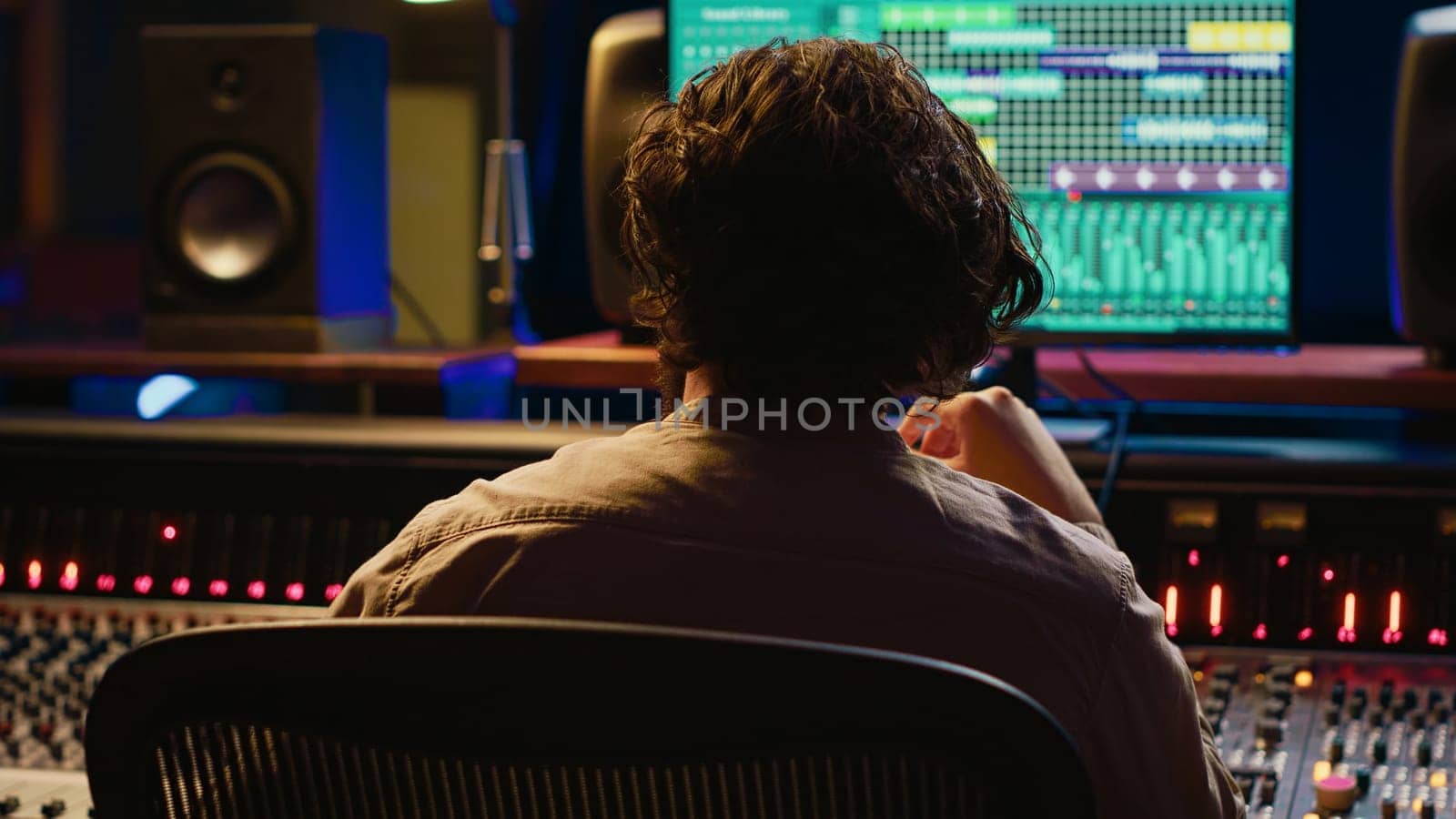 Skilled sound designer enjoying his own music creating at mixing console by DCStudio