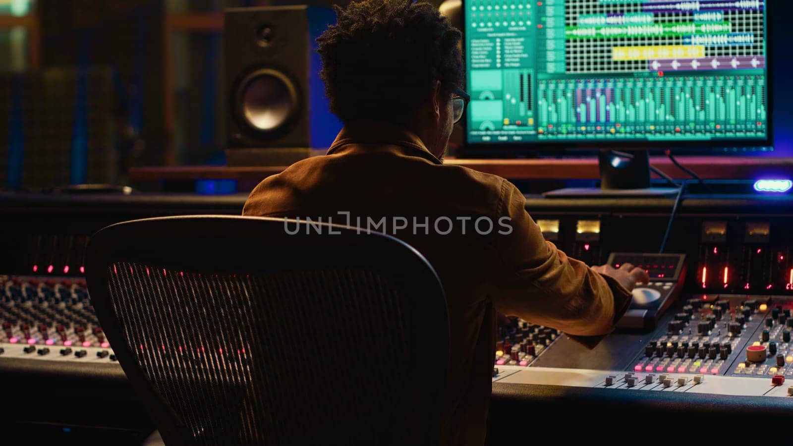 Sound designer relaxing on studio chair after mixing and mastering tracks, finishing his musical project in control room. African american audio expert producing new songs. Camera A.
