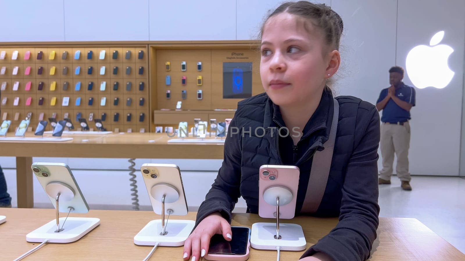 Denver, Colorado, USA-March 23, 2024-curious little girl examines the latest iPhone models on display at the Apple Store located in Park Meadows Mall, showcasing a youthful interest in technology.