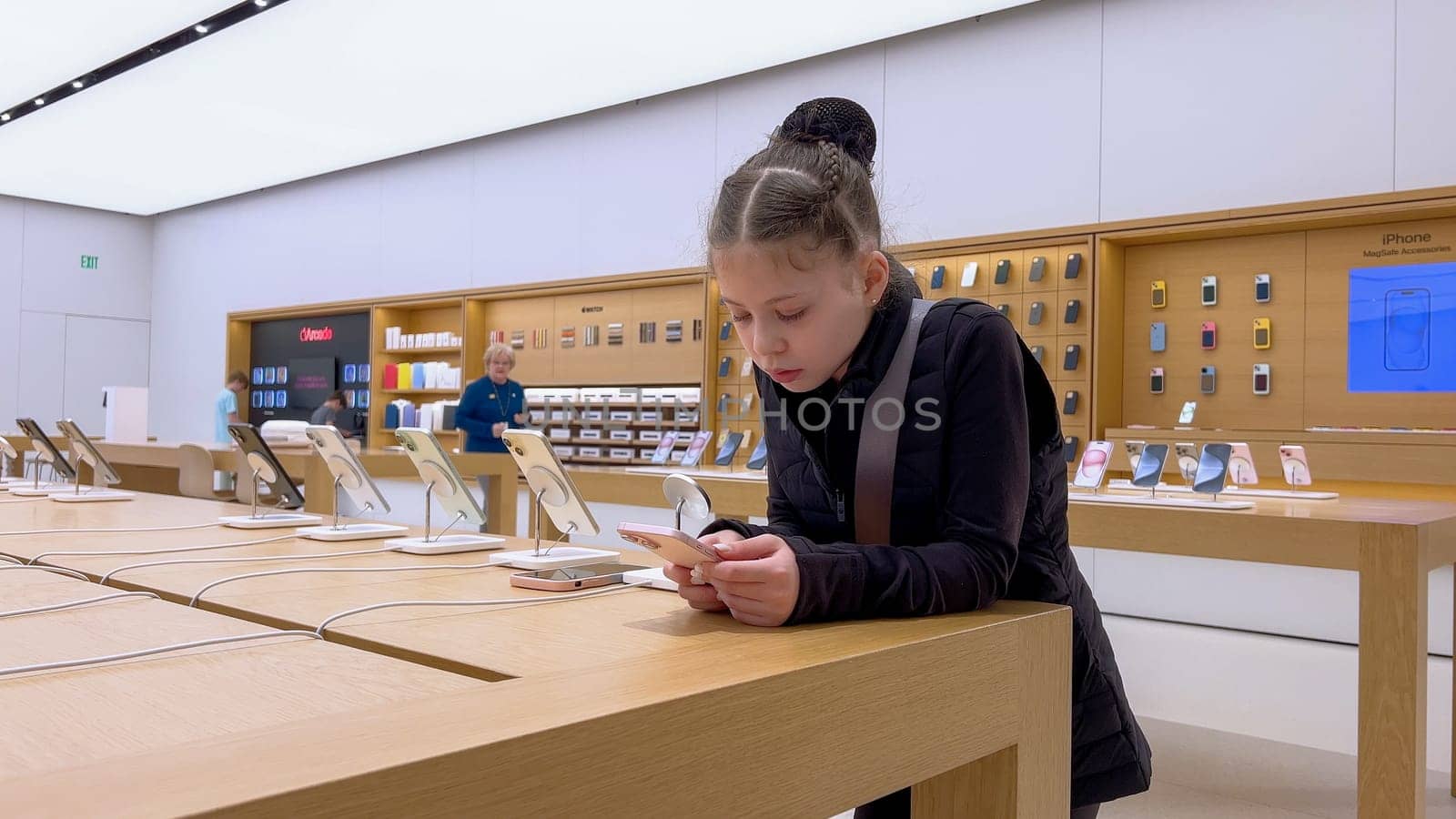 Denver, Colorado, USA-March 23, 2024-curious little girl examines the latest iPhone models on display at the Apple Store located in Park Meadows Mall, showcasing a youthful interest in technology.