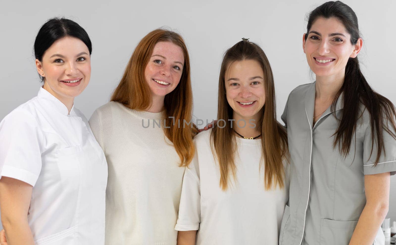 Group portrait of cosmetologists in uniform smiling at camera by andreonegin