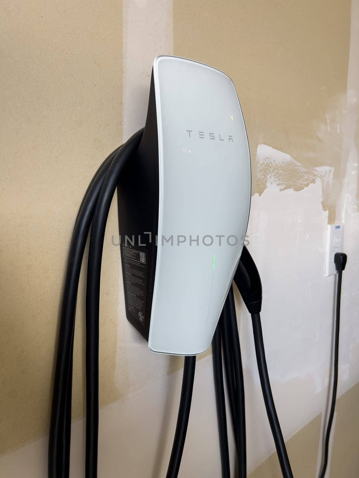 Tesla Wall Connector Installed in a Home Garage for Electric Car Charging by arinahabich