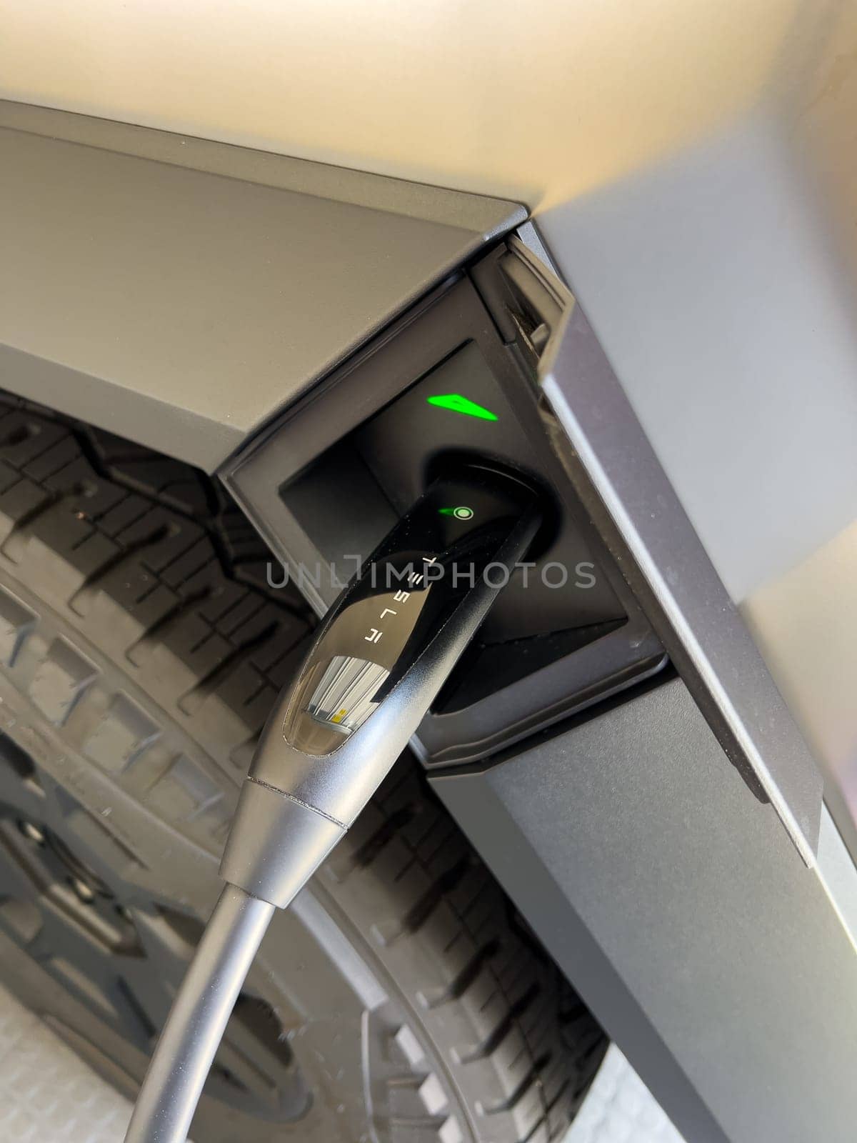 Denver, Colorado, USA-March 28, 2024-close-up view of a Tesla Cybertruck being charged, with the connector firmly plugged in, as indicated by the illuminated green lights, in a private suburban house garage.