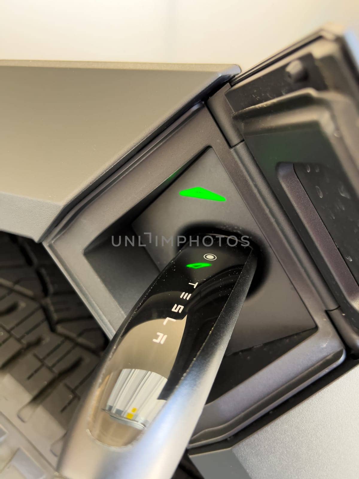 Denver, Colorado, USA-March 28, 2024-close-up view of a Tesla Cybertruck being charged, with the connector firmly plugged in, as indicated by the illuminated green lights, in a private suburban house garage.