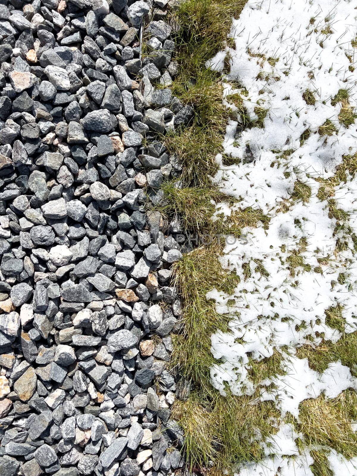 Spring Snow Melting on Suburban Landscaping Gravel and Grass by arinahabich