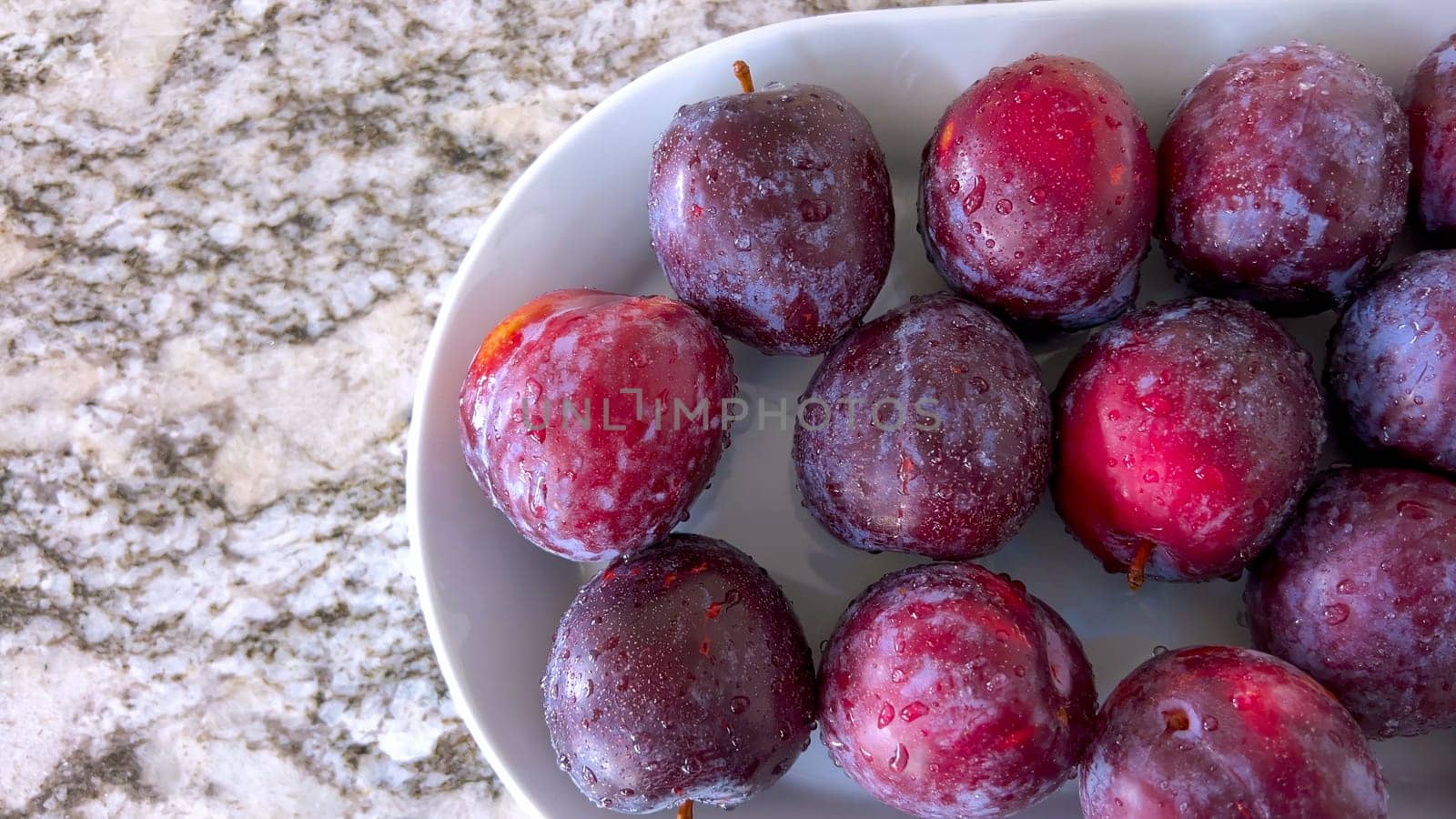 Ripe Plums Arranged on a Kitchen Countertop by arinahabich
