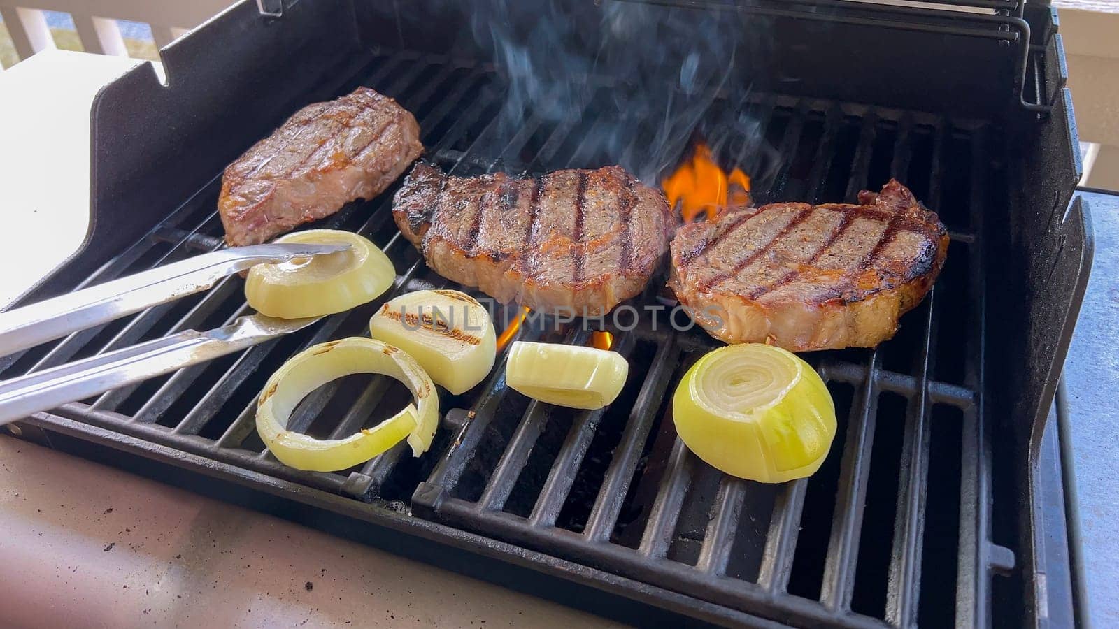 Summer Barbecue with Ribeye Steaks and Grilled Onions on the Grill by arinahabich