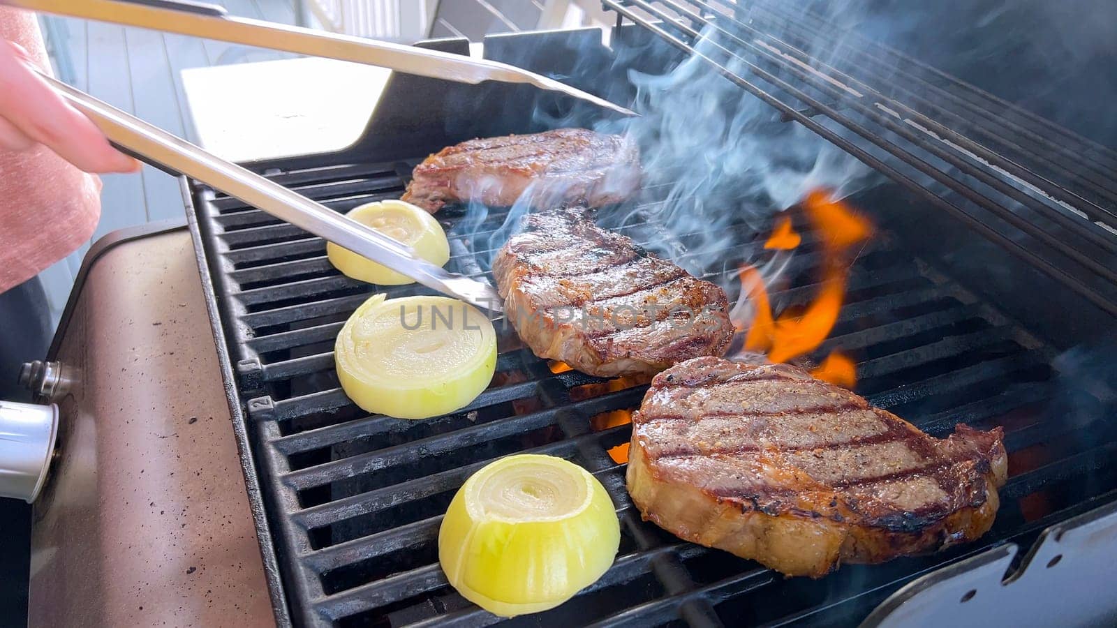 Summer Barbecue with Ribeye Steaks and Grilled Onions on the Grill by arinahabich