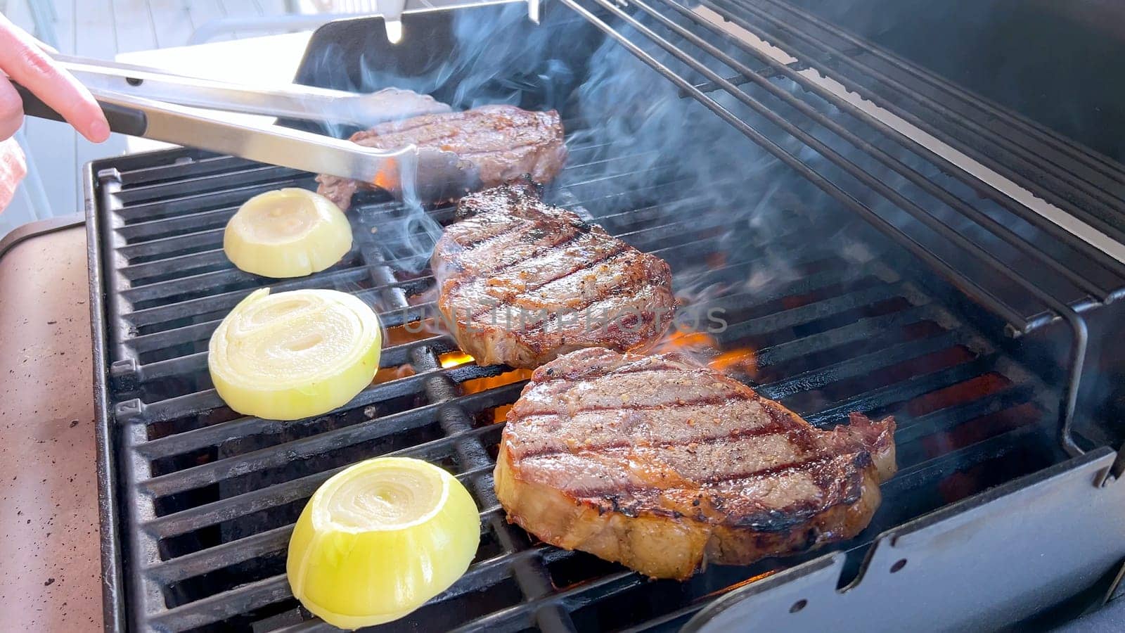 Summer Barbecue with Ribeye Steaks and Grilled Onions on the Grill by arinahabich