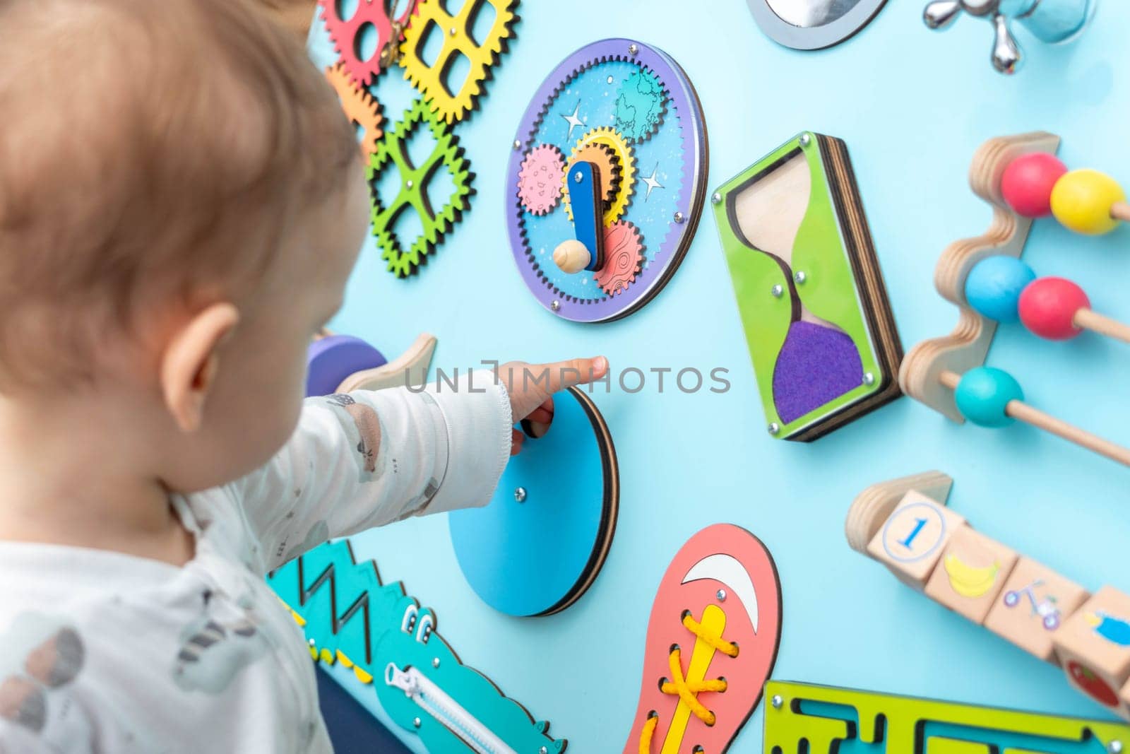 Baby with a small hand reaches for a busy board by sdf_qwe
