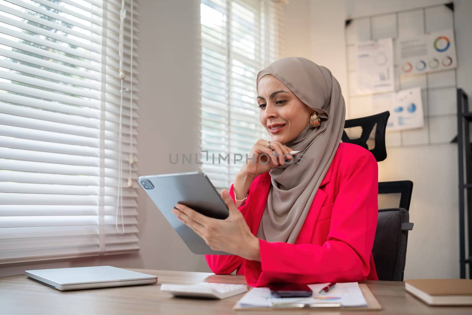 Confident Muslim businesswoman supervisor checks work on holiday and works in home office.