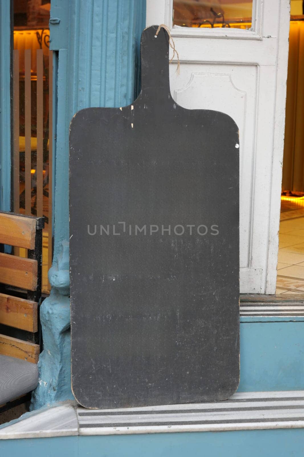 Empty wooden blackboard mockup standing outdoors in front of cafe .