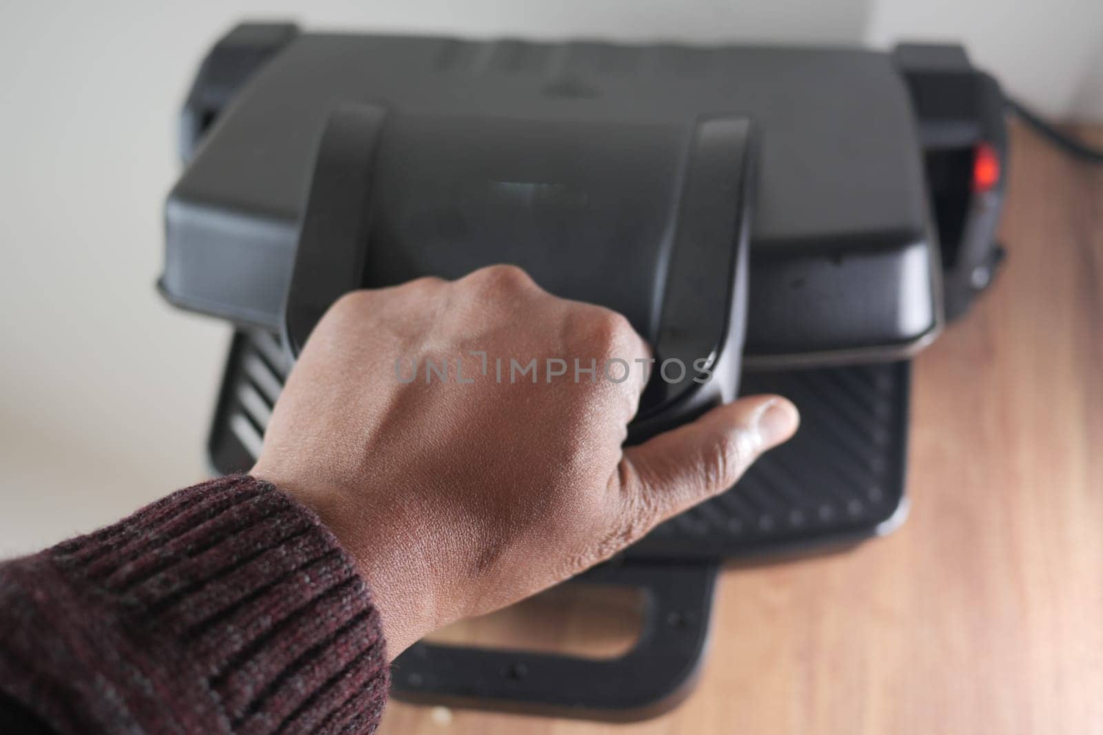 Hand using finger to press button on grill gadget,