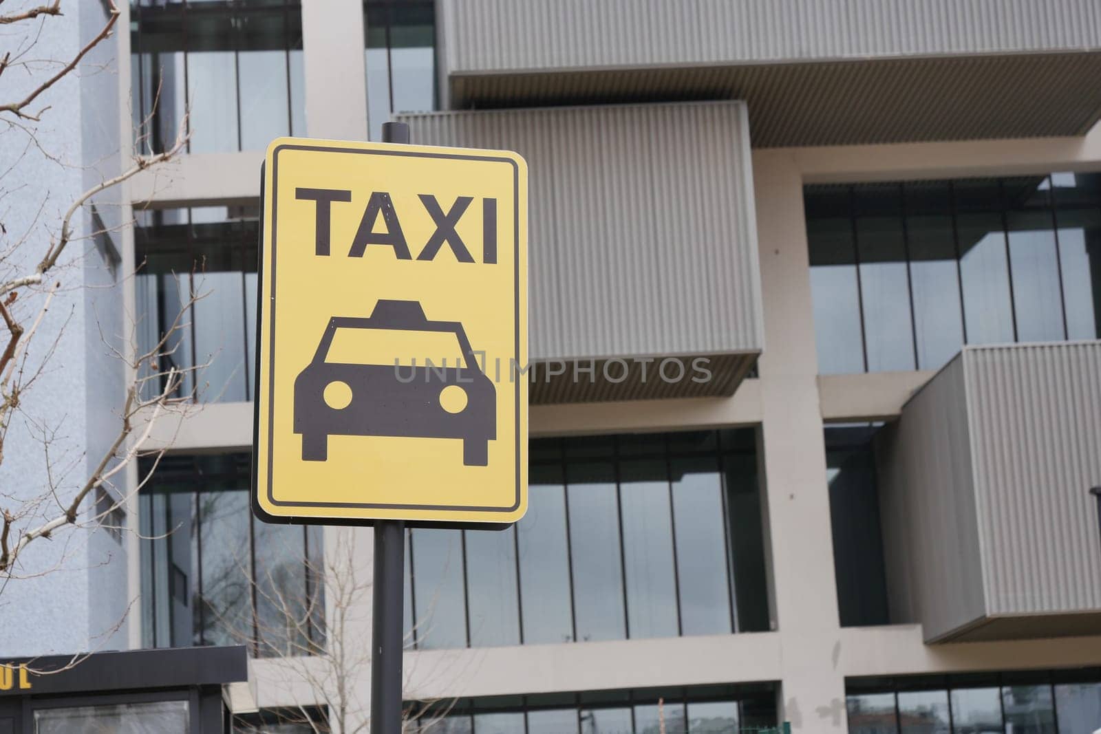 Close-up photo of a yellow Taxi stand sign attached to a metal pole.