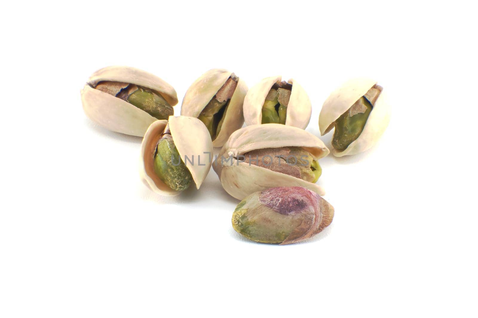 Randomly spread pistachios isolated on white by NetPix