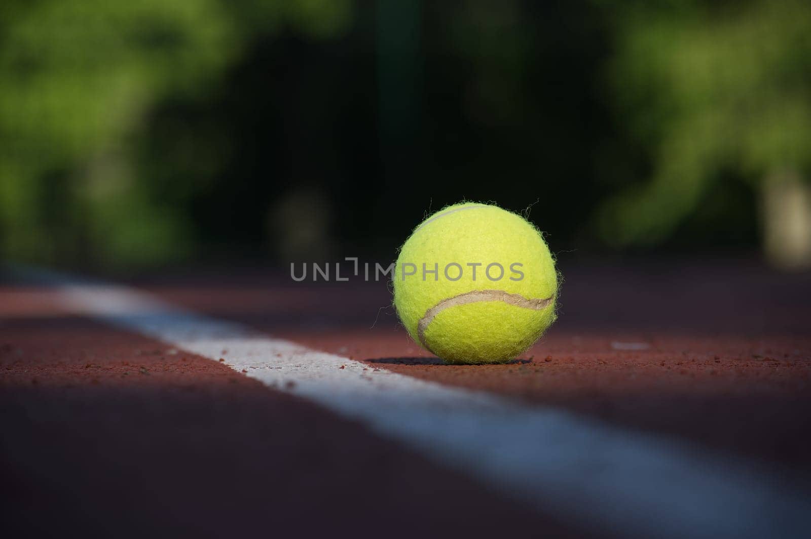 Tennis ball on hard court surface near white line by NetPix