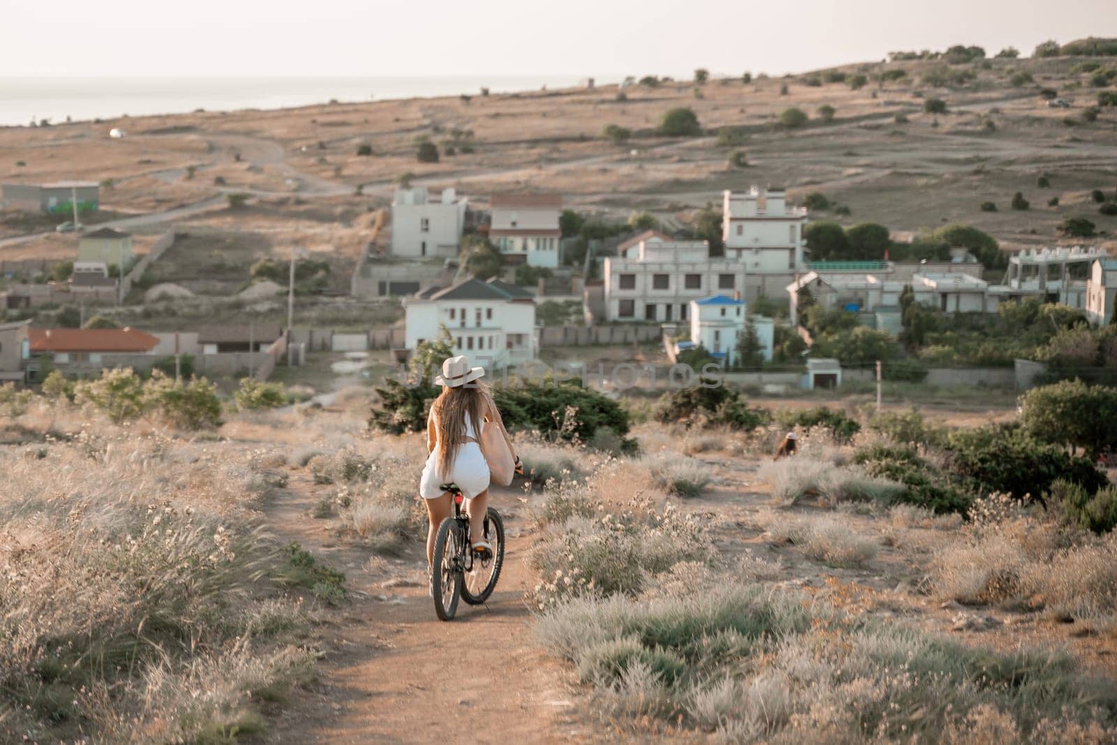 A woman cyclist on a mountain bike looking at the landscape sea. Adventure travel on bike