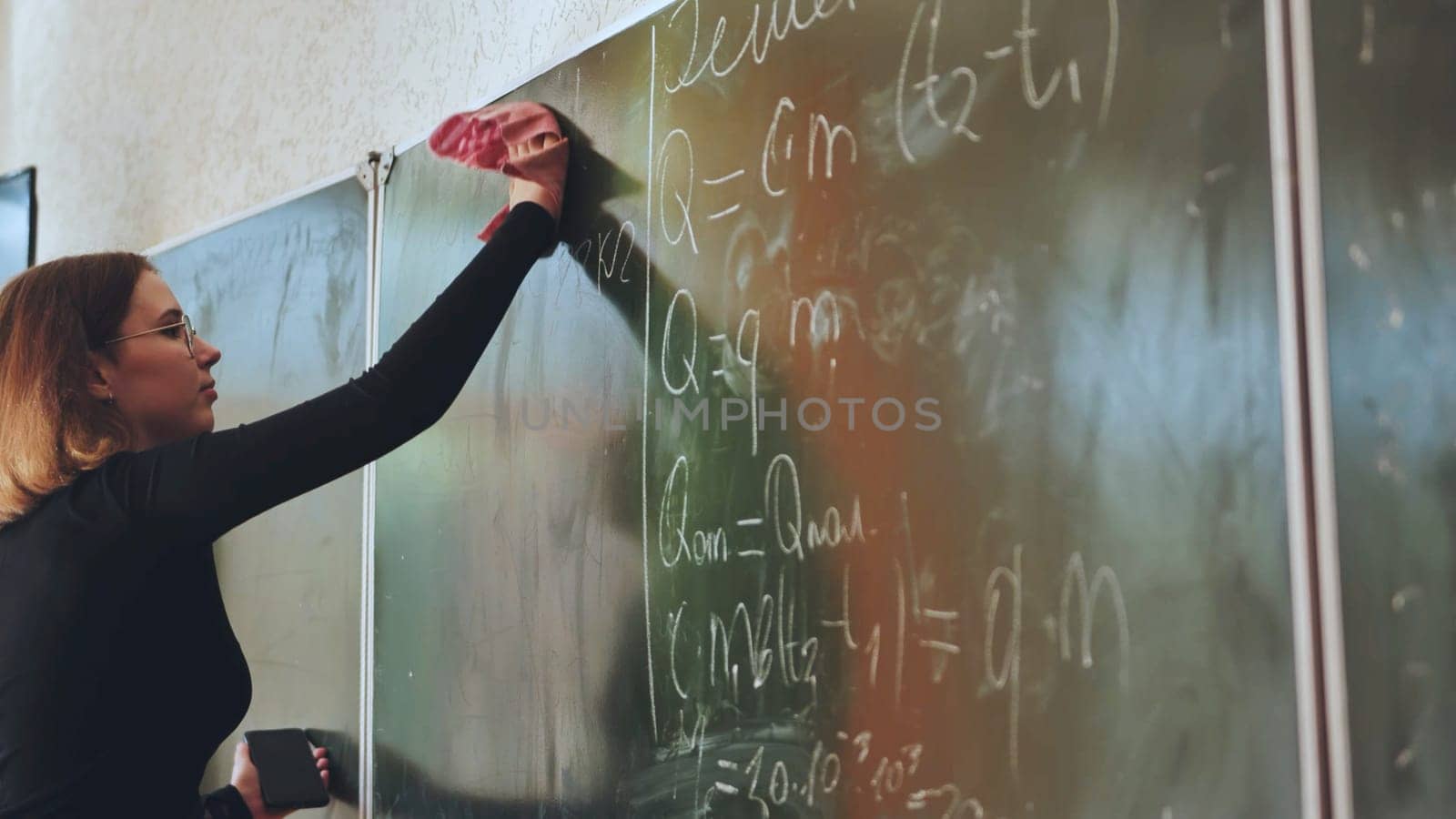 A girl washes the school blackboard after a maths lesson