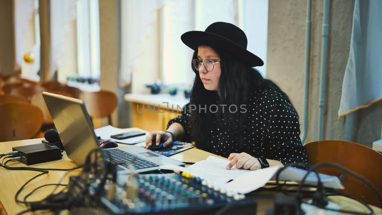 A schoolgirl wearing a hat at a mixing console and computer before an event. by DovidPro