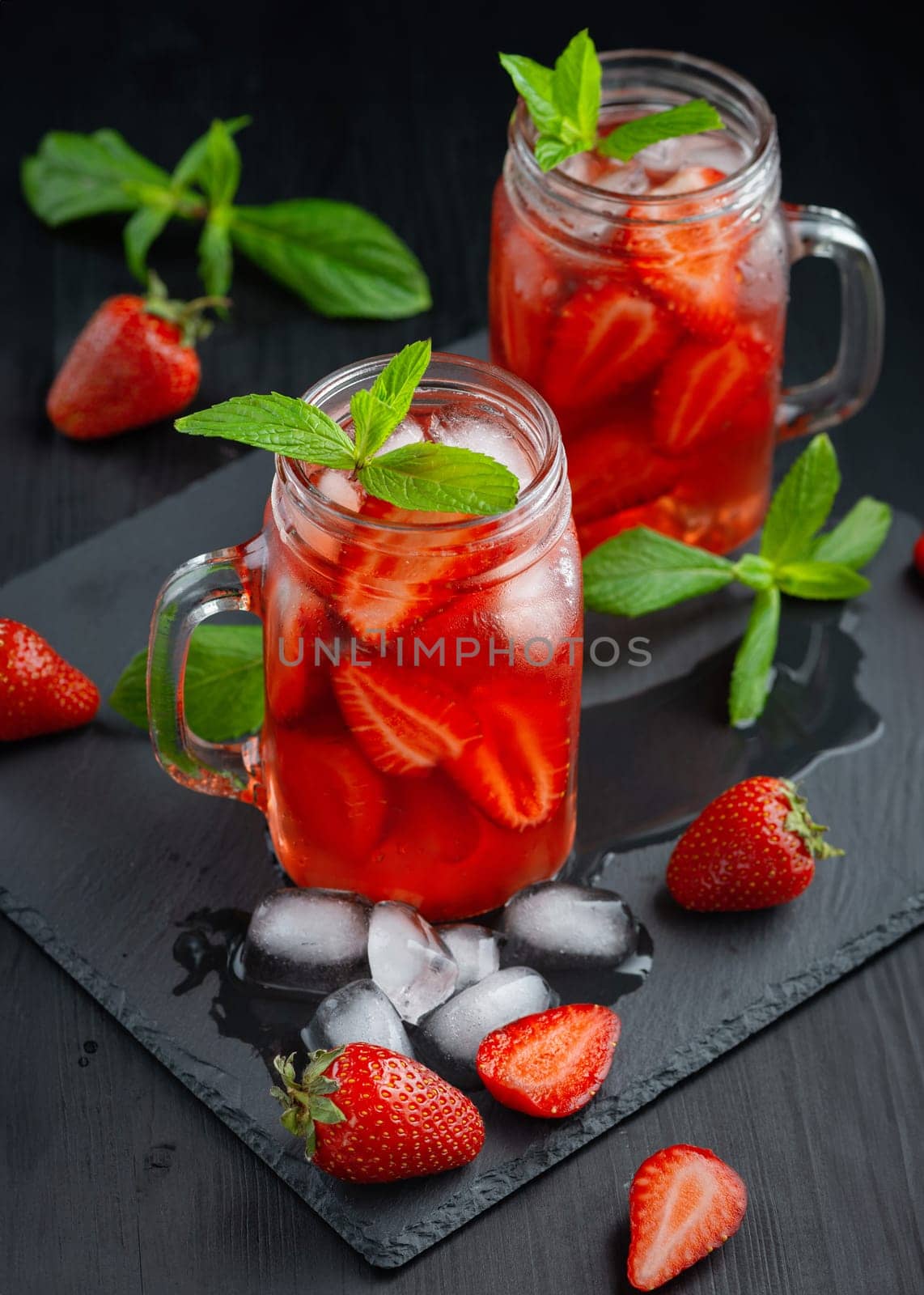 Fresh strawberry cocktail. Fresh summer cocktail with strawberry and ice cubes. Glass of strawberry drink on dark background.