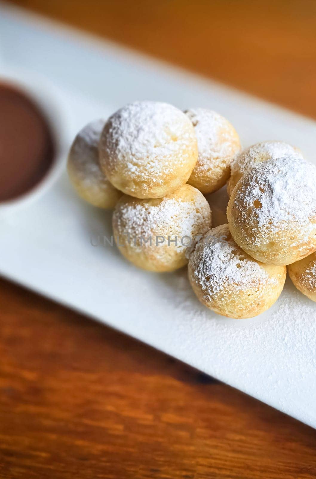 Homemade Dutch poffertjes mini pancakes with icing powdered sugar and chocolate fillings with additional chocolate sauce for delicious desserts