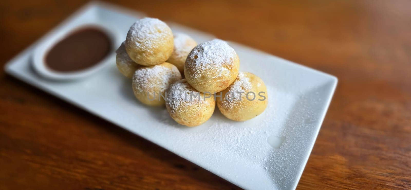 Homemade Dutch poffertjes mini pancakes with icing powdered sugar and chocolate fillings with additional chocolate sauce by antoksena