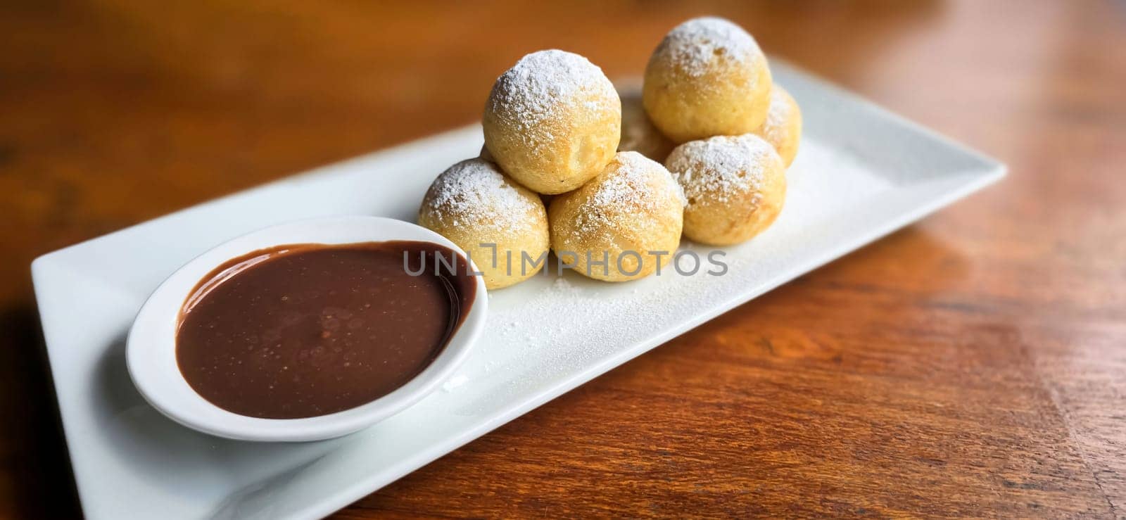 Homemade Dutch poffertjes mini pancakes with icing powdered sugar and chocolate fillings with additional chocolate sauce by antoksena