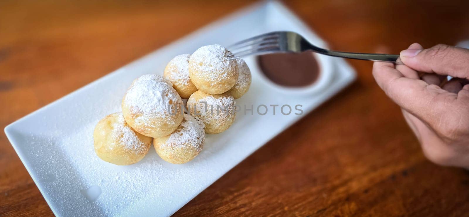 Homemade Dutch poffertjes mini pancakes with icing powdered sugar and chocolate fillings with additional chocolate sauce for delicious desserts