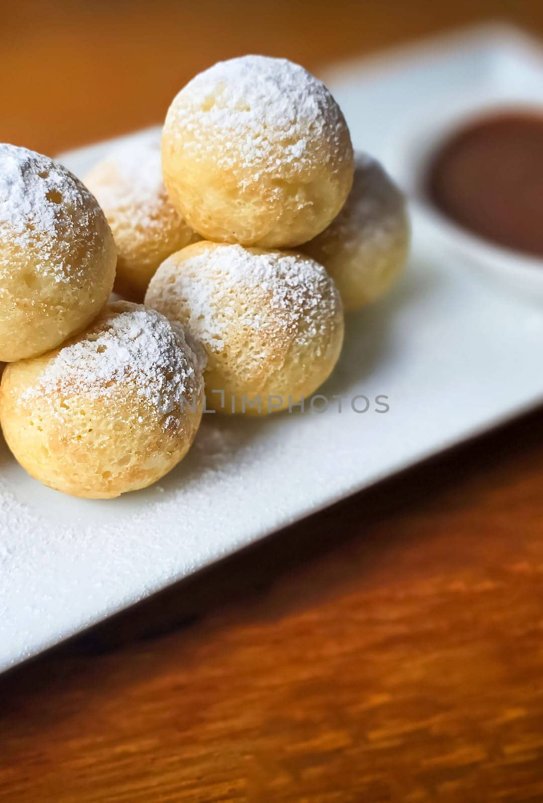 Homemade Dutch poffertjes mini pancakes with icing powdered sugar and chocolate fillings with additional chocolate sauce by antoksena
