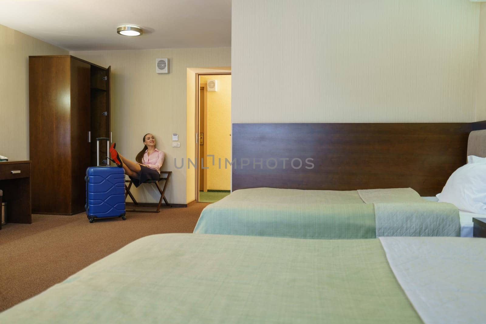 Hotel room. Woman poses while puts her feet on suitcase
