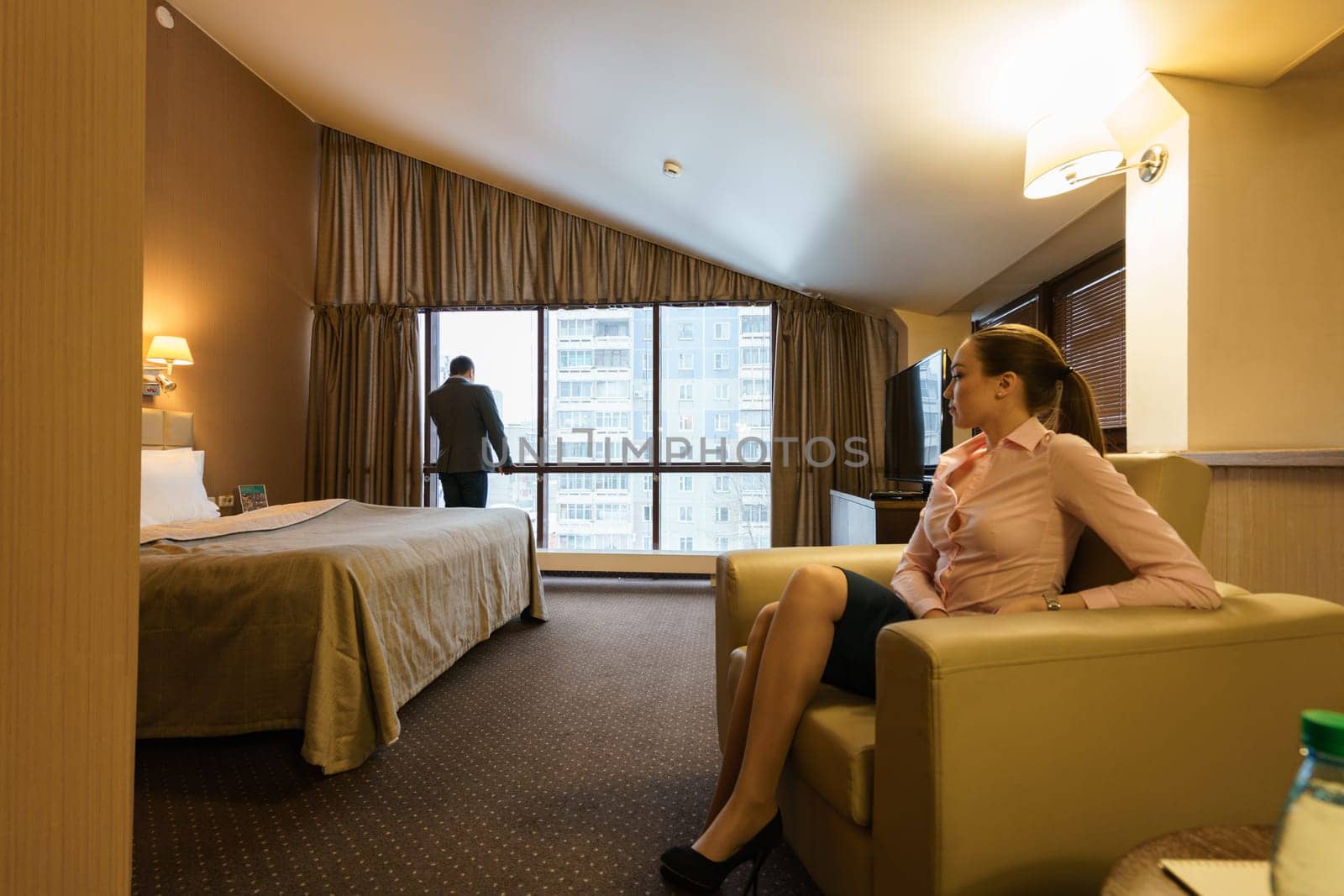 Woman sits in chair and her business partner standing at window