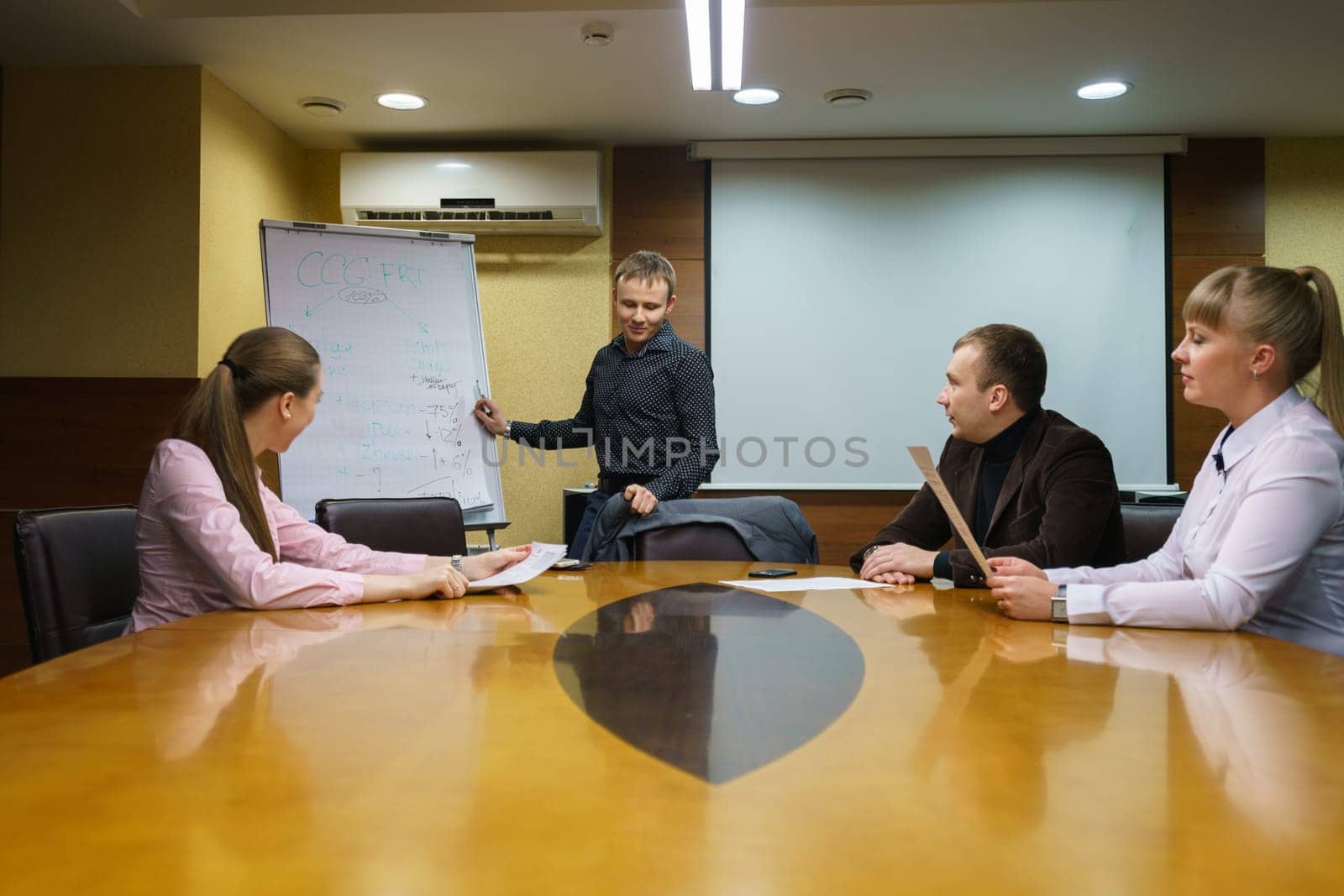 Image of young man leading conference for business people