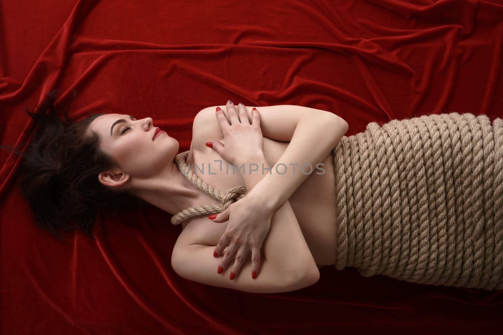 Shibari. Top view of woman tied with rope lying in bed